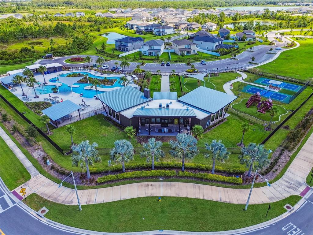 A row of two-story townhomes with gray siding, white board-and-batten accents, and attached garages — 31357 AMBERVIEW BEND, WESLEY CHAPEL, FL