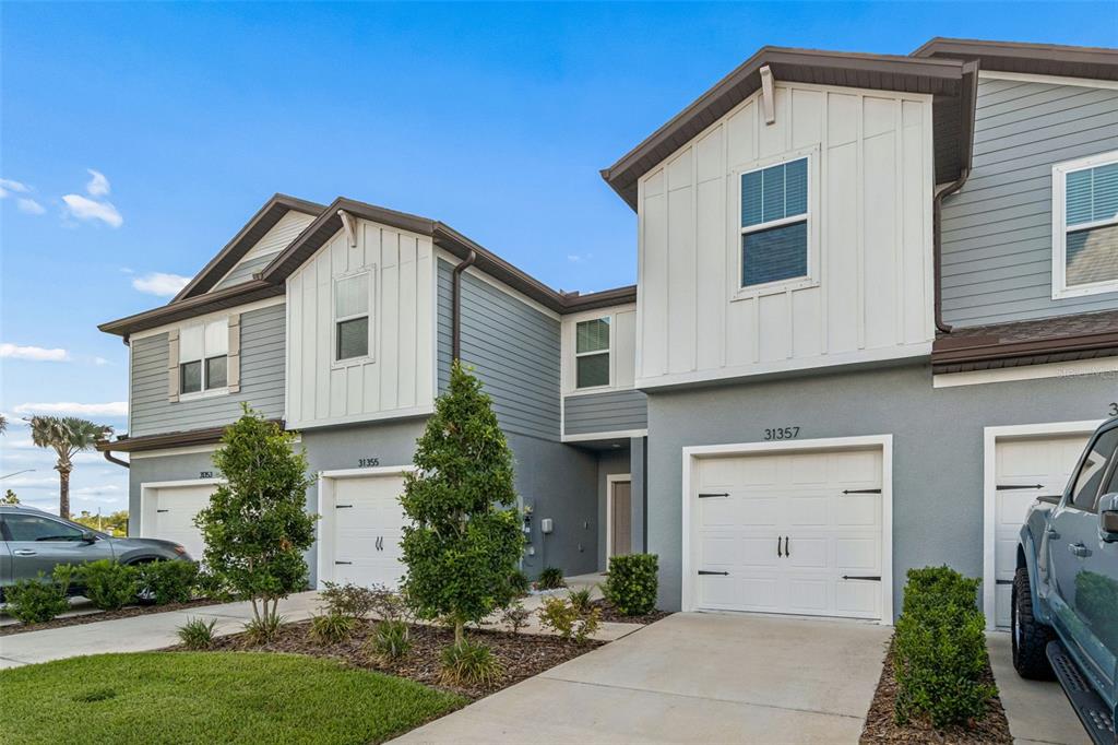 An entryway features a carpeted staircase, tiled flooring, a gray bench, and a view beyond — 31357 AMBERVIEW BEND, WESLEY CHAPEL, FL