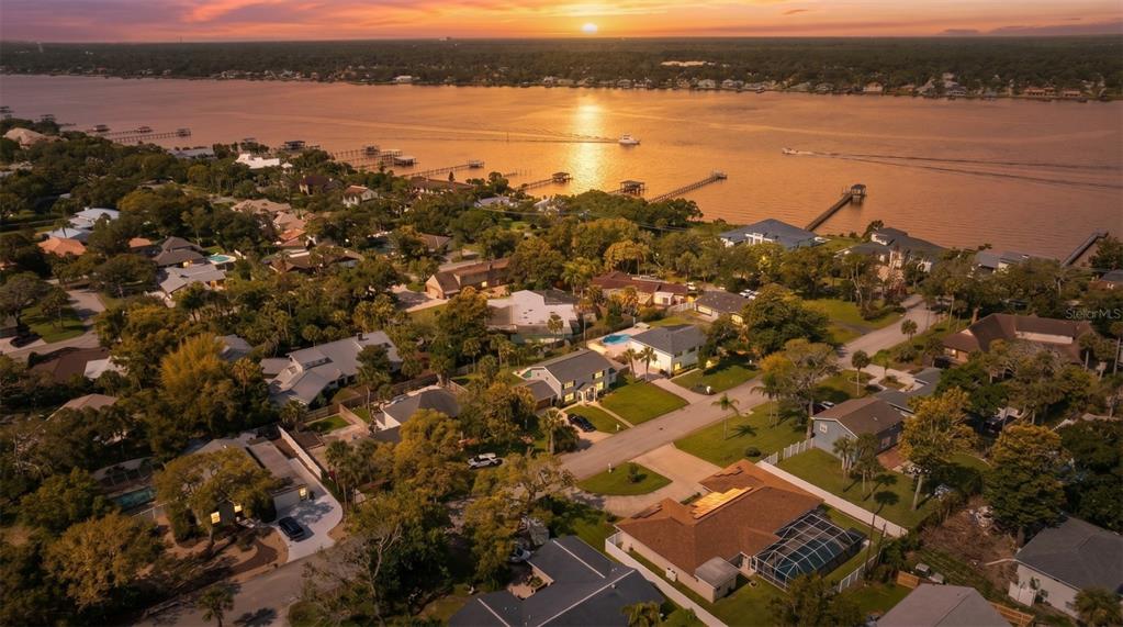 An aerial view of a residential neighborhood along a river at sunset — 33 SANDCASTLE DRIVE, ORMOND BEACH, FL