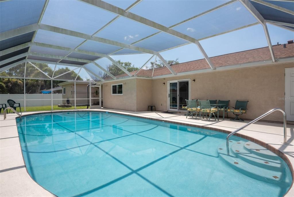 A swimming pool with a screened-in enclosure and a patio area next to a house — 33 SANDCASTLE DRIVE, ORMOND BEACH, FL