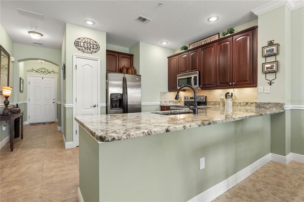 A kitchen features dark wood cabinets, granite countertops, a breakfast bar, and light green walls — 75 RIVERVIEW BEND S UNIT 1624, PALM COAST, FL