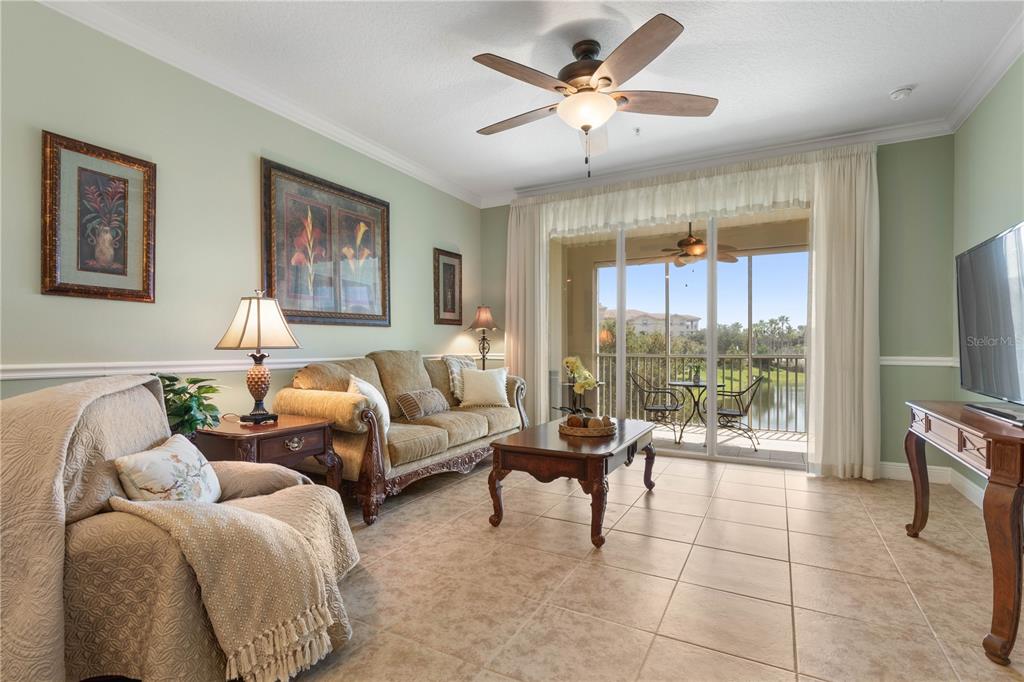 A living room with tile floors, a ceiling fan, a sofa, and a sliding glass door — 75 RIVERVIEW BEND S UNIT 1624, PALM COAST, FL