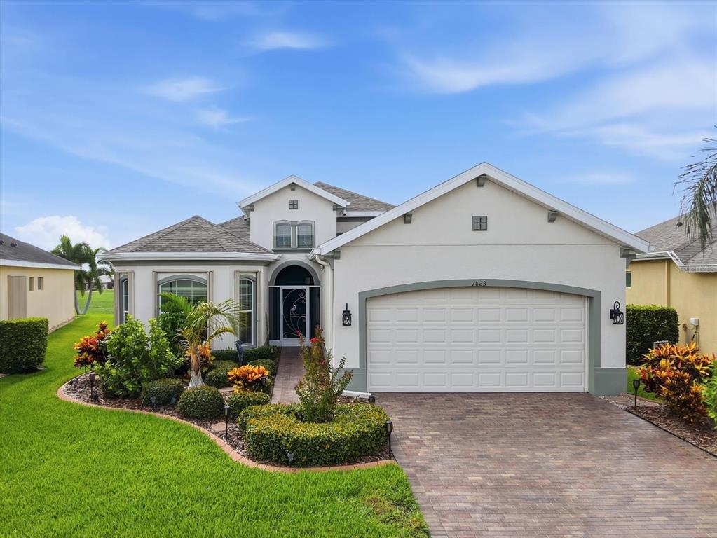 A single-story house with a two-car garage, a paved driveway, and landscaped front yard — 1823 PACIFIC DUNES DRIVE, SUN CITY CENTER, FL