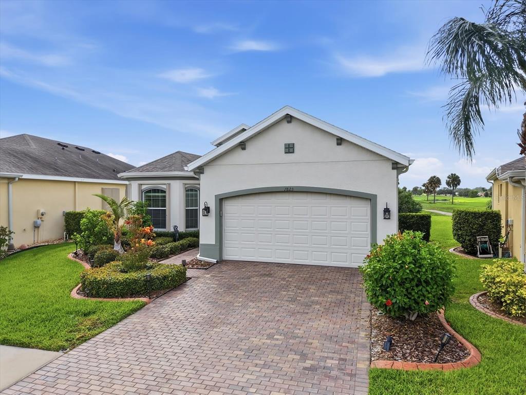 A single-story house with a white stucco exterior, a two-car garage, and a paver driveway — 1823 PACIFIC DUNES DRIVE, SUN CITY CENTER, FL