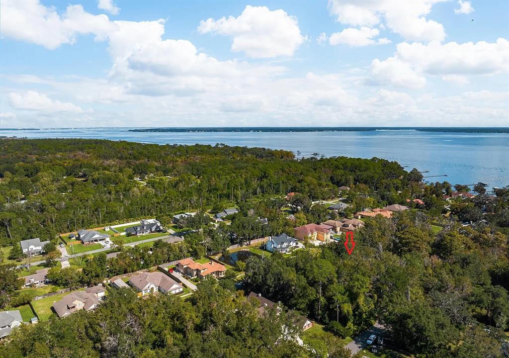 An aerial view shows a wooded residential neighborhood near a large body of water — RIVERWOOD DRIVE, FLEMING ISLAND, FL