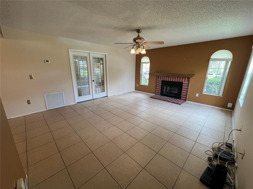 A living room features tile flooring, a brick fireplace, and glass French doors — 11940 SKYLAKE PLACE UNIT 11940-A, TEMPLE TERRACE, FL