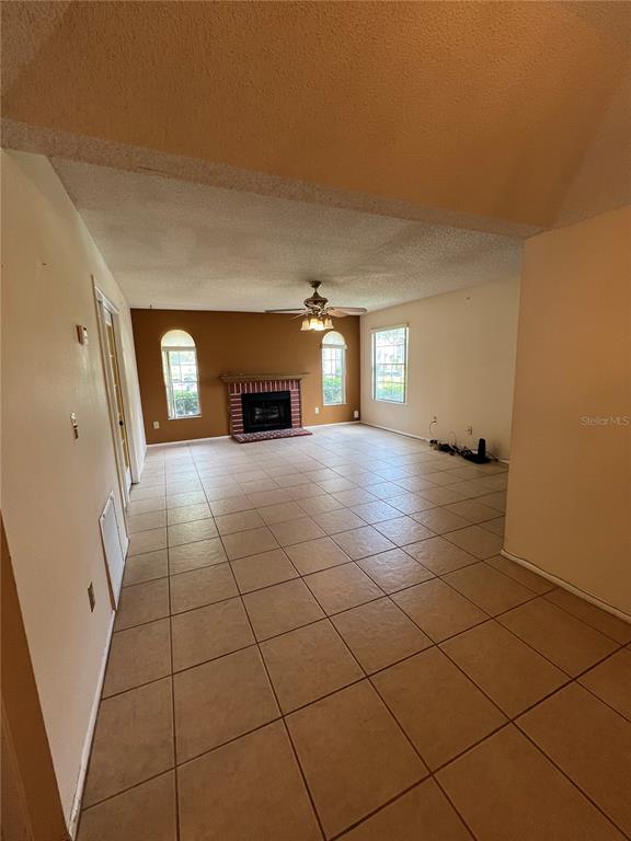 A spacious room with tiled floors, a fireplace, and a ceiling fan — 11940 SKYLAKE PLACE UNIT 11940-A, TEMPLE TERRACE, FL