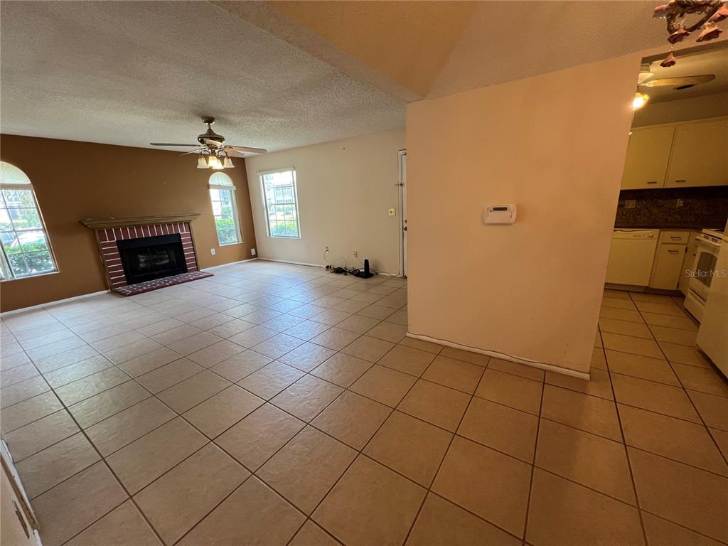 A living room with tile flooring, a fireplace, and an adjacent kitchen — 11940 SKYLAKE PLACE UNIT 11940-A, TEMPLE TERRACE, FL