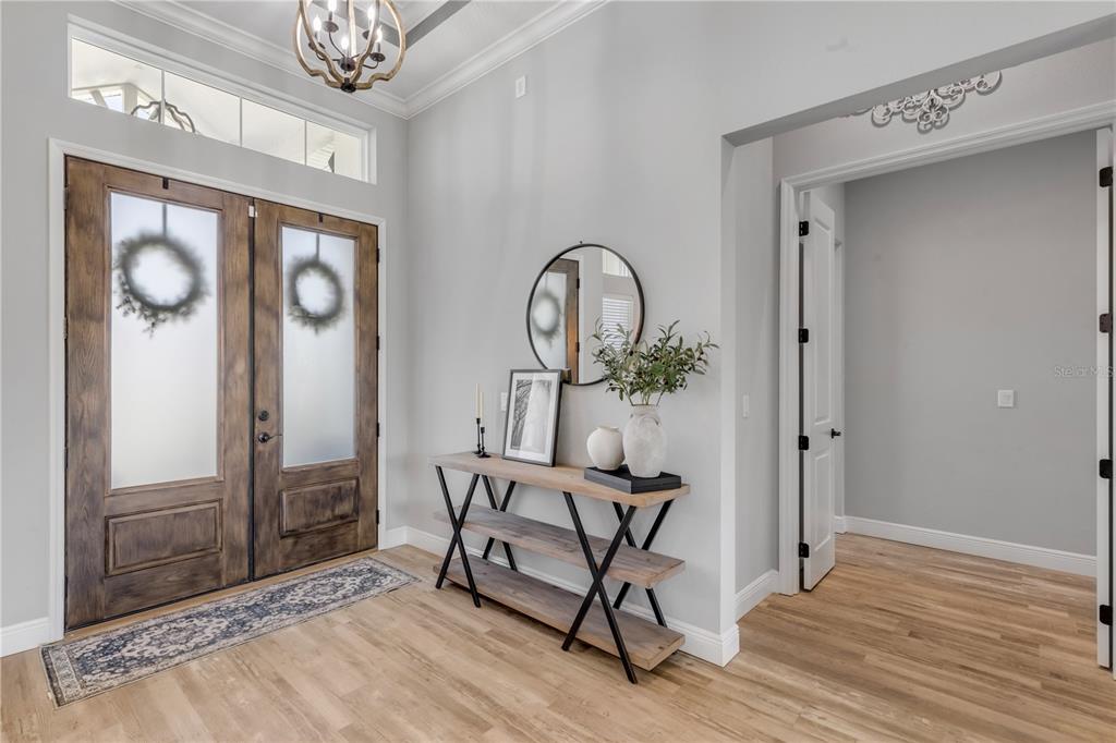 A bright entryway features wood-look flooring, a rustic console table, and double front doors — 3055 ISOLA BELLA BOULEVARD, MOUNT DORA, FL