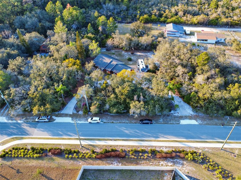 An aerial view shows a house nestled in a wooded lot with two driveways — 6365 WHIP O WILL LANE, ST CLOUD, FL
