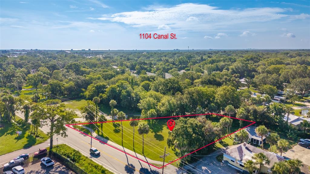 An aerial view shows a vacant, grassy lot outlined in red next to a road — 1104 CANAL STREET, NEW SMYRNA BEACH, FL