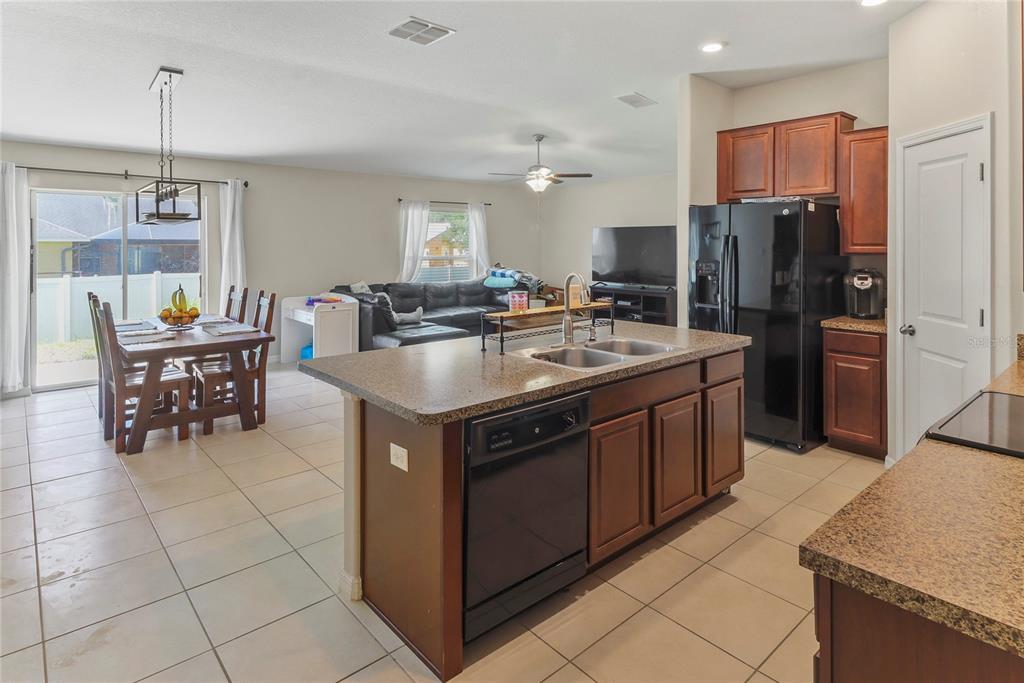 An open-concept kitchen with a central island overlooks a dining area and living room — 135 CASCADE BEND DRIVE, RUSKIN, FL