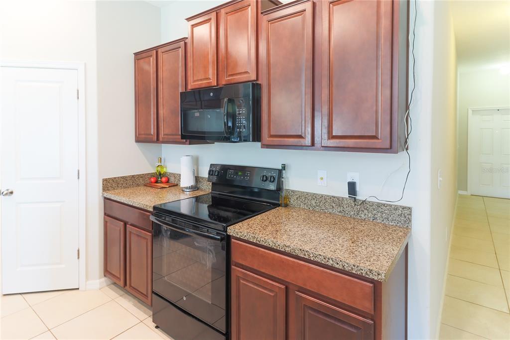 A kitchen features dark wood cabinets, granite countertops, and black appliances — 135 CASCADE BEND DRIVE, RUSKIN, FL