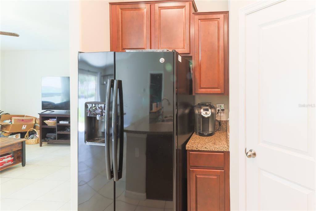 A kitchen area features a black refrigerator, wooden cabinets, and a small coffee station — 135 CASCADE BEND DRIVE, RUSKIN, FL