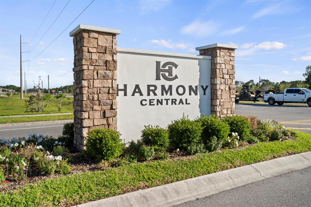 A stone-columned monument sign for Harmony Central stands beside a paved road — 4224 SAGEFIELD DRIVE, HARMONY, FL