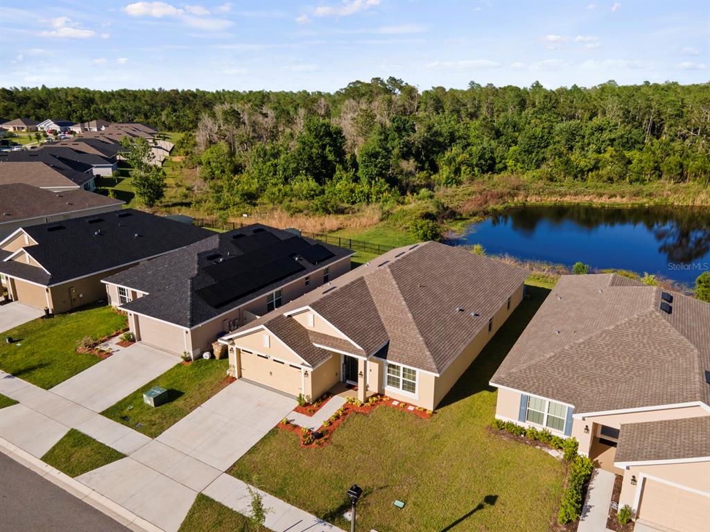 An aerial view shows suburban houses with driveways, a pond, and a wooded background — 4224 SAGEFIELD DRIVE, HARMONY, FL