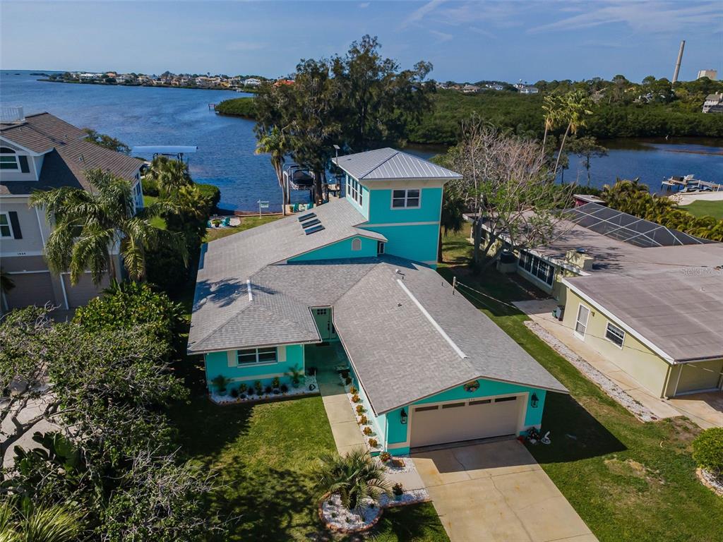 A grassy backyard overlooks a waterfront dock and palm trees during a vibrant sunset — 1626 SEA BREEZE DRIVE, TARPON SPRINGS, FL