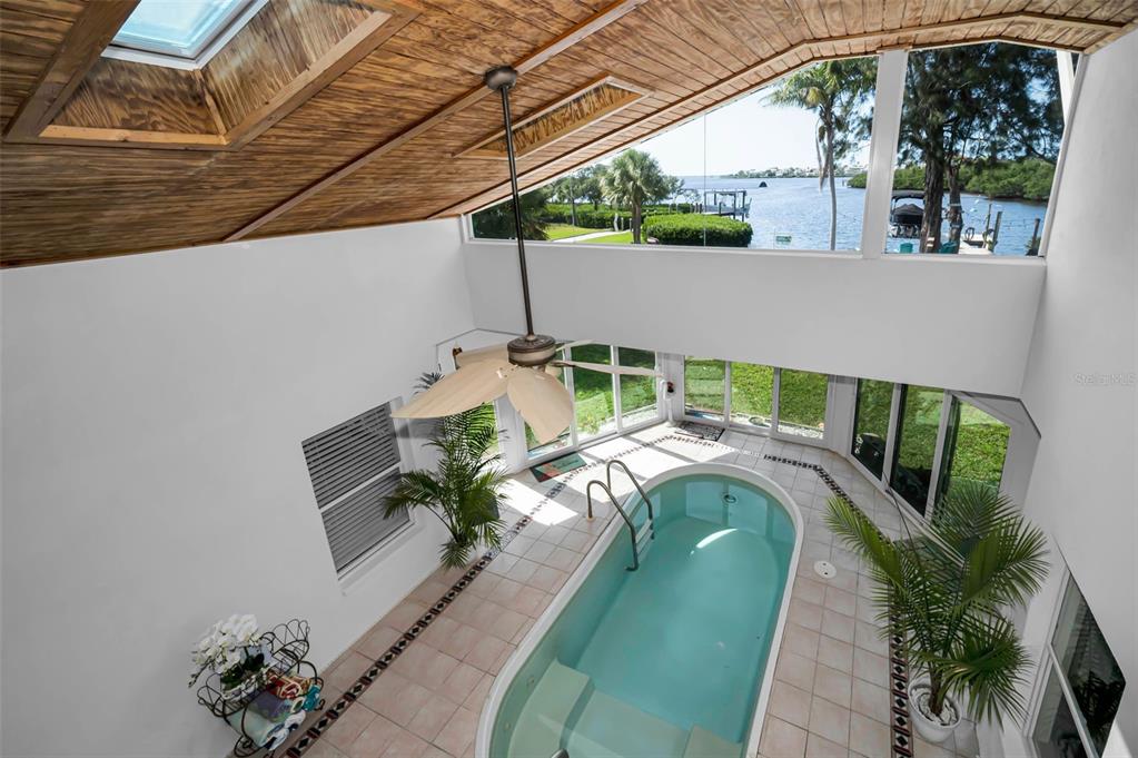 A wooden dock with turquoise chairs extends into the water under string lights at sunset — 1626 SEA BREEZE DRIVE, TARPON SPRINGS, FL