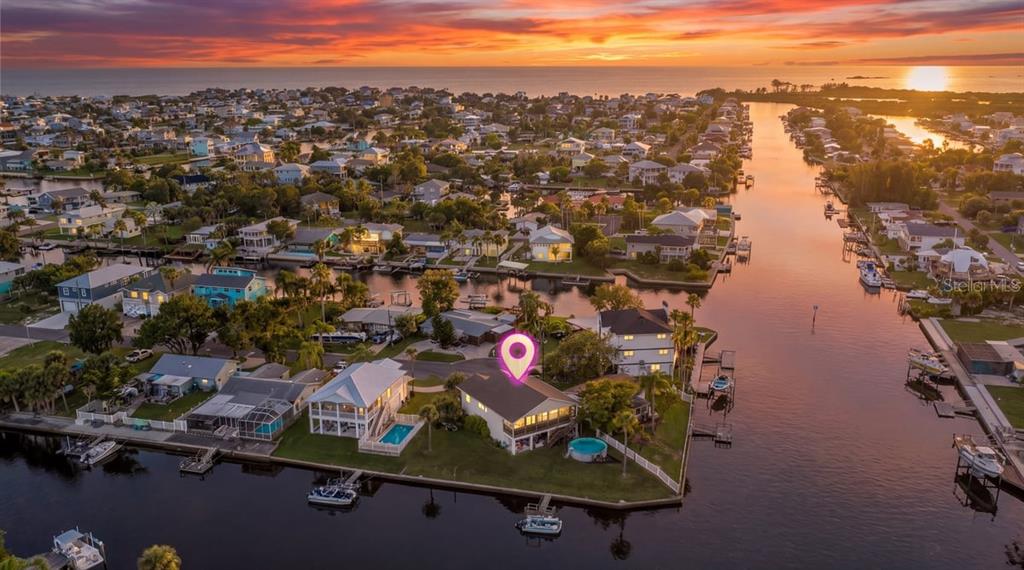 An aerial view shows a waterfront house with a pool and dock on a corner lot — 4514 NEPTUNE DRIVE, HERNANDO BEACH, FL