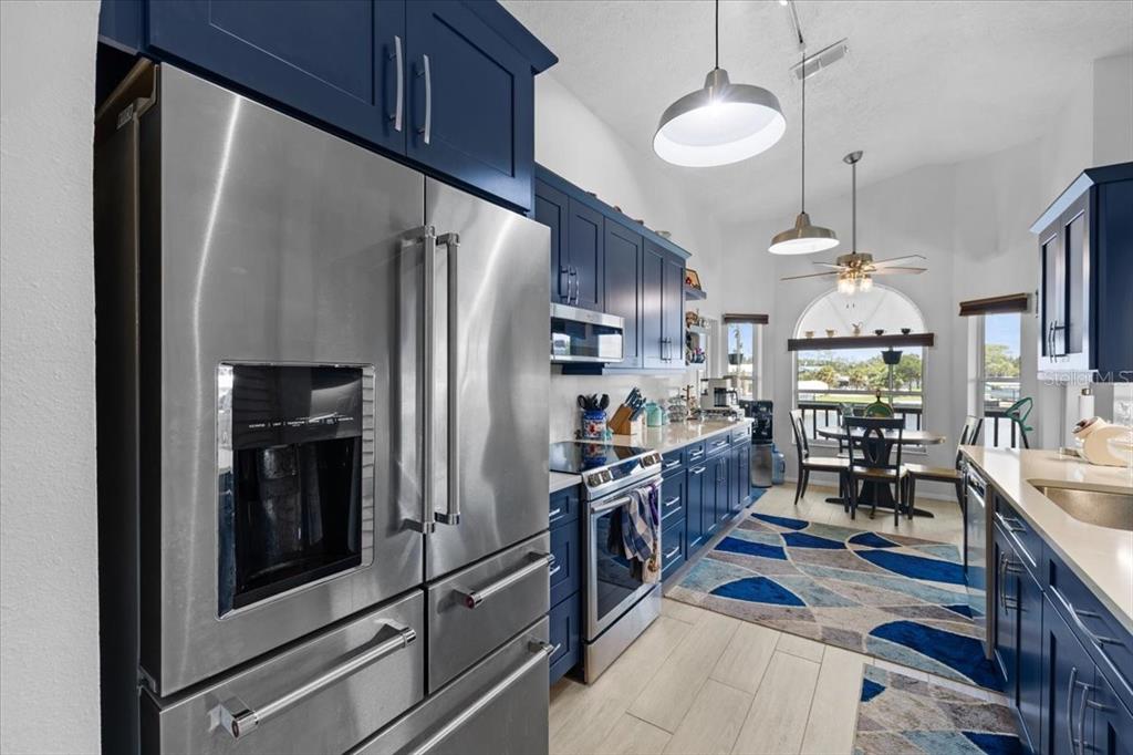 A kitchen features blue cabinets, stainless steel appliances, and a dining area with a rug — 4514 NEPTUNE DRIVE, HERNANDO BEACH, FL