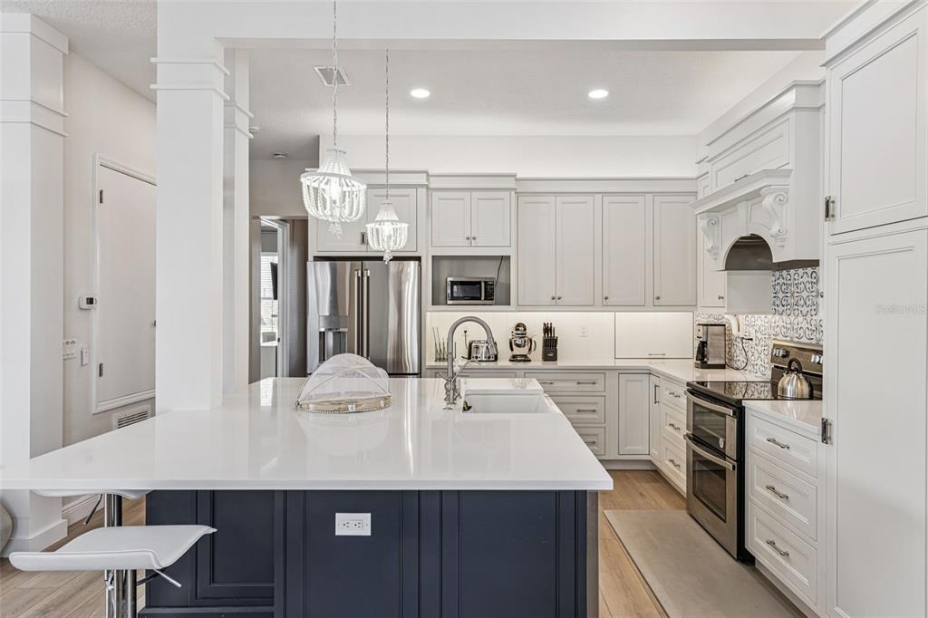 A kitchen features a dark blue island with a white countertop and white cabinetry — 7494 GATHERING DRIVE, REUNION, FL