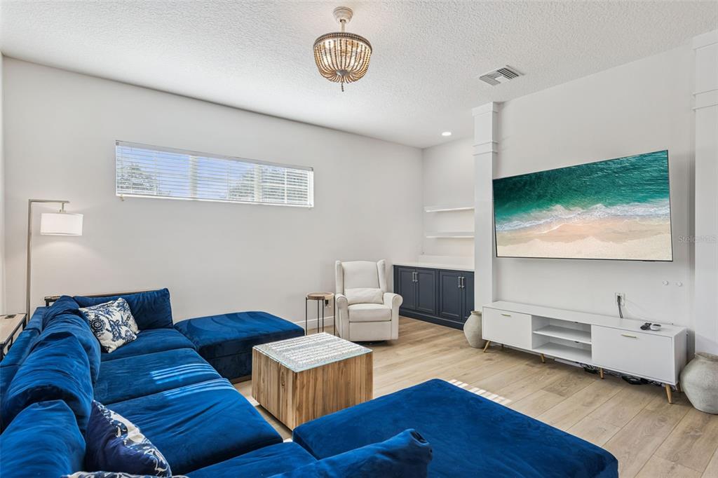 A living room features a large blue sectional sofa, a white media console, and light flooring — 7494 GATHERING DRIVE, REUNION, FL