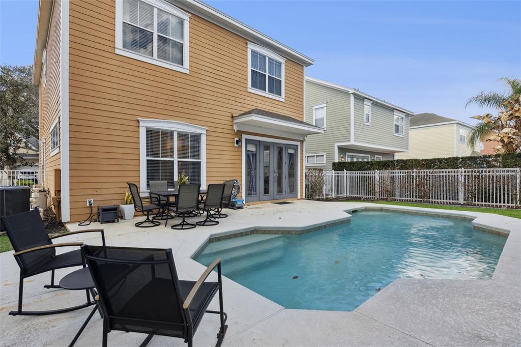 A two-story house with tan siding features a backyard pool and a patio dining set — 7494 GATHERING DRIVE, REUNION, FL