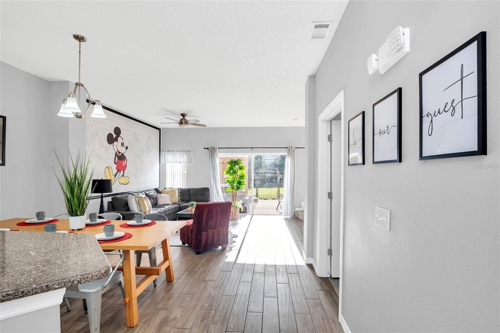A dining area and living room with wood-look tile floors and a Mickey Mouse mural — 4706 VERO BEACH PLACE, KISSIMMEE, FL