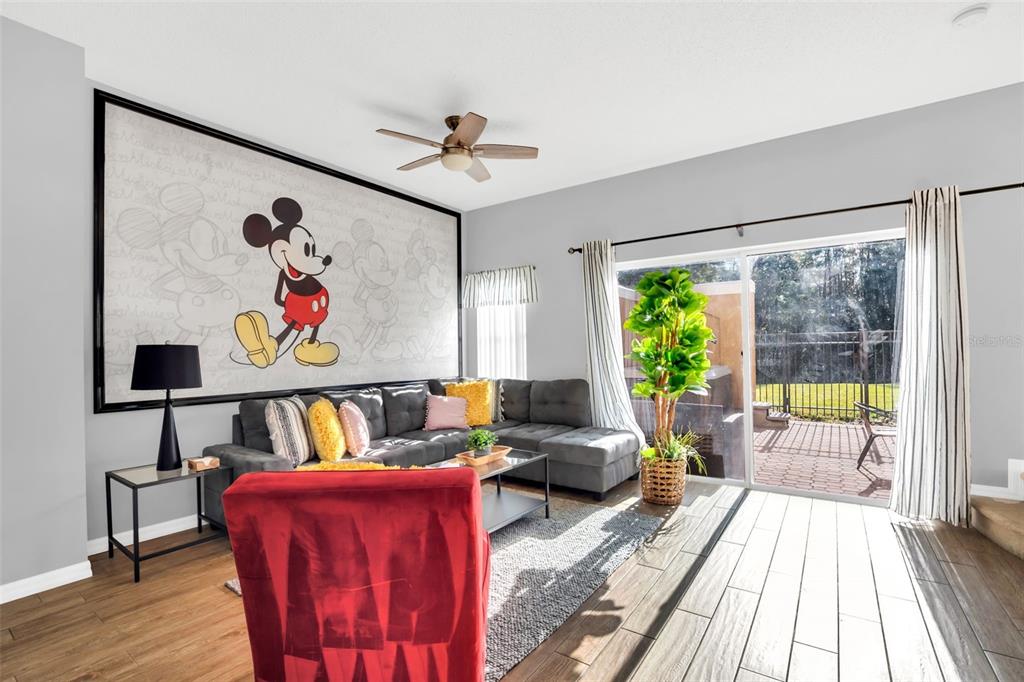 A living room features a large Mickey Mouse wall mural, gray sectional sofa, and patio access — 4706 VERO BEACH PLACE, KISSIMMEE, FL