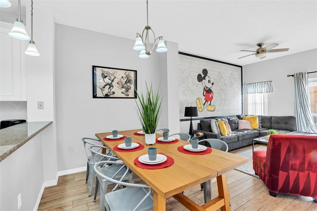 A dining area with a wooden table and Mickey Mouse-themed wall art and decor — 4706 VERO BEACH PLACE, KISSIMMEE, FL