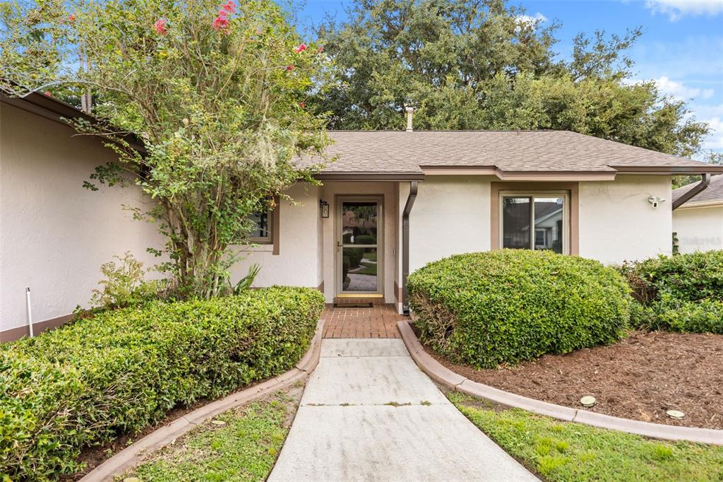 A concrete walkway leads to the front entrance of a single-story house with landscaping — 11813 SCOTTY DRIVE, ORLANDO, FL