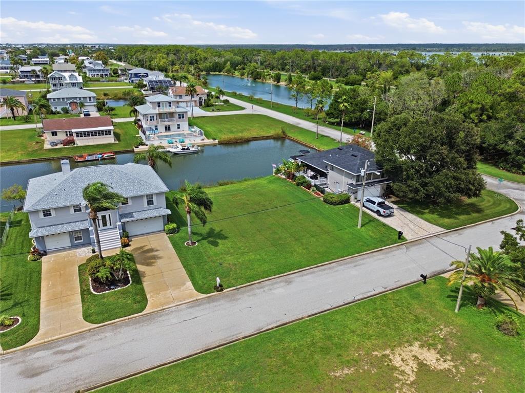 An aerial view shows two houses separated by a large, grassy lot along a canal — 4057 JEWFISH DRIVE, HERNANDO BEACH, FL
