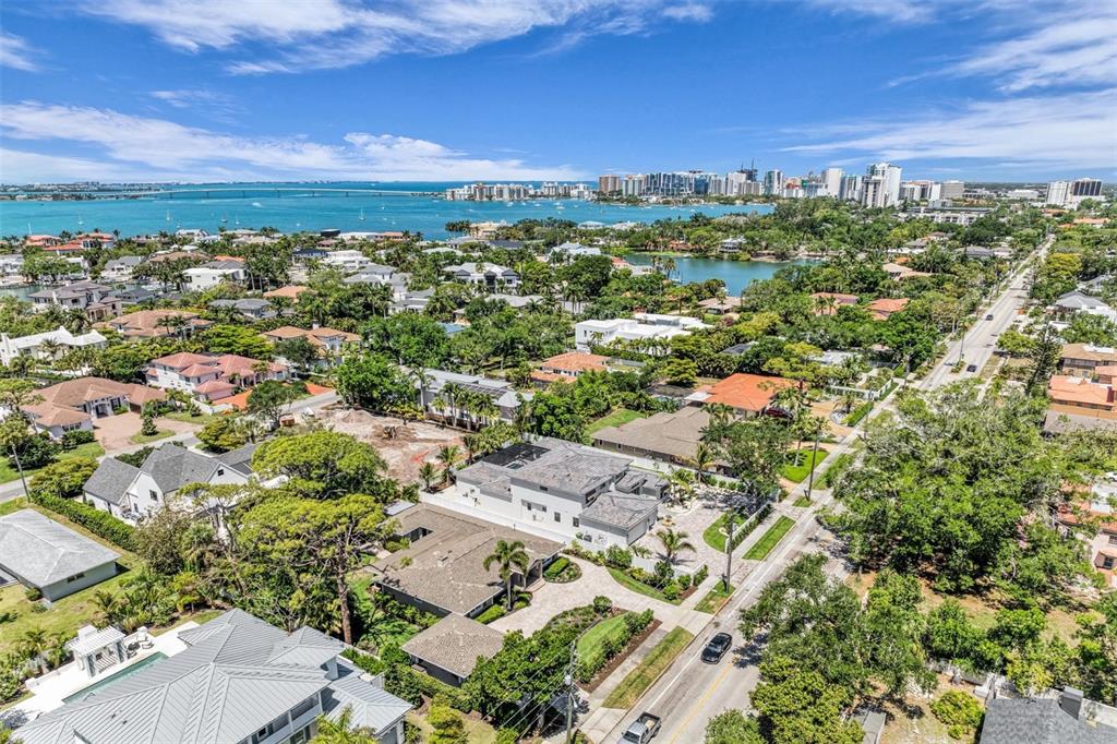 An aerial view shows a coastal neighborhood with houses, lush trees, and a large bay — 1395 HARBOR DRIVE, SARASOTA, FL