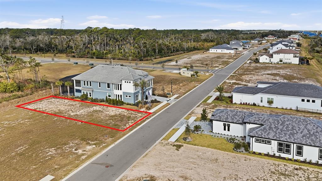 An aerial view shows a vacant rectangular lot outlined in red next to a house — 87 CORONADO ROAD, FLAGLER BEACH, FL