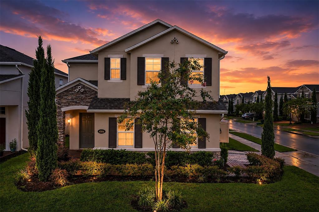 A two-story suburban house with a stone facade, dark shutters, and a landscaped front yard — 4504 LATIMER WAY, SANFORD, FL