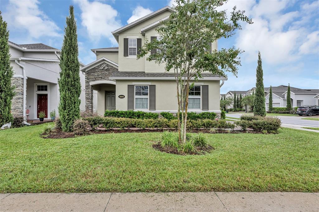 A two-story suburban house with a stone facade, green siding, and a manicured front lawn — 4504 LATIMER WAY, SANFORD, FL