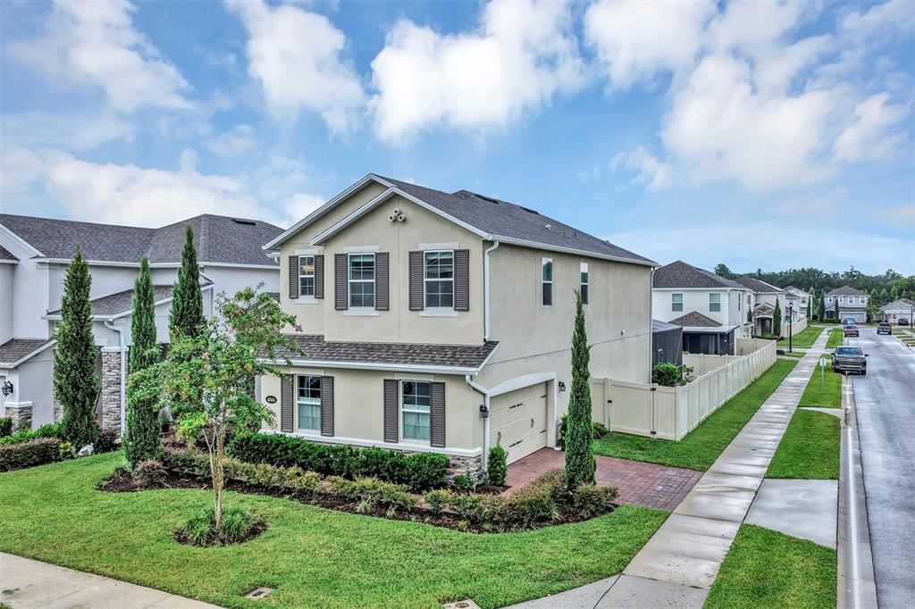 A two-story suburban house with a beige stucco exterior, dark shutters, and a paved driveway — 4504 LATIMER WAY, SANFORD, FL