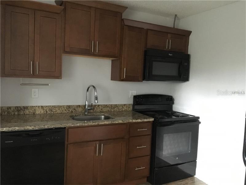 A kitchen features dark wood cabinets, granite countertops, and black appliances — 508 VARSITY STREET, WINTER GARDEN, FL