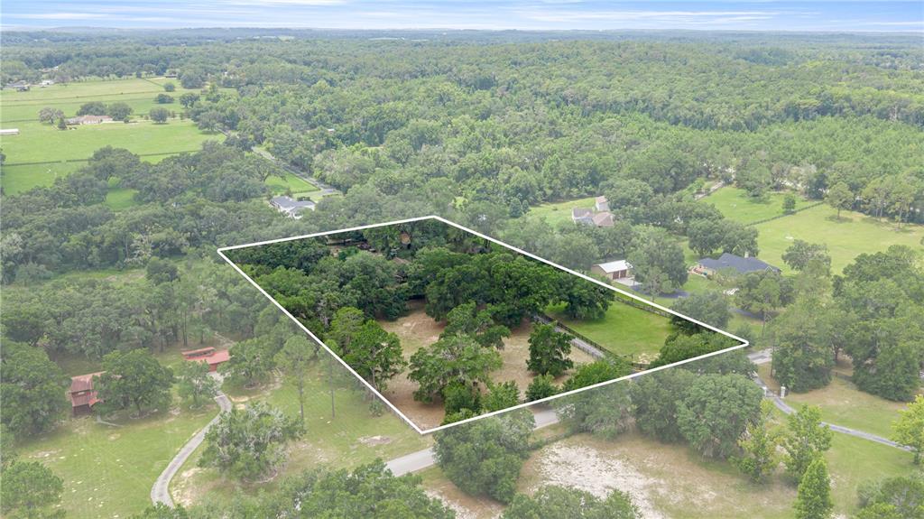 An aerial view shows a fenced, tree-filled residential lot surrounded by rural landscape — 4556 E VIEW TOP LANE, INVERNESS, FL