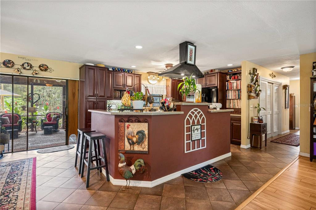 A kitchen features dark wood cabinets, a central island with a rooster motif, and tile flooring — 4556 E VIEW TOP LANE, INVERNESS, FL