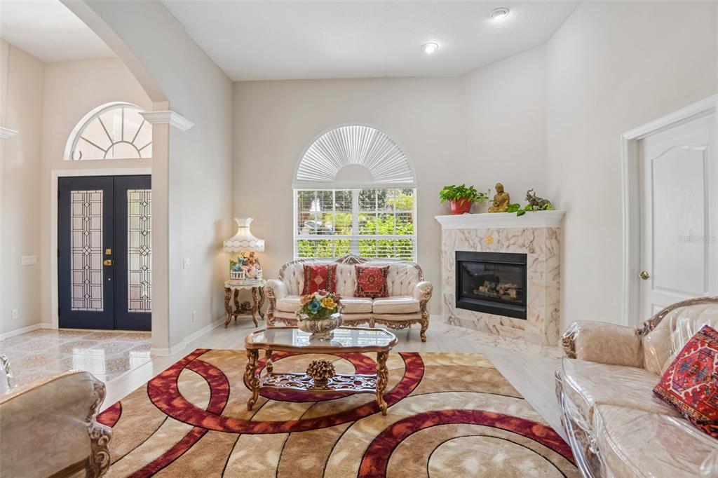 A living room features a fireplace, arched windows, ornate furniture, and a patterned area rug — 1701 COUNTRY TRAILS DRIVE, SAFETY HARBOR, FL