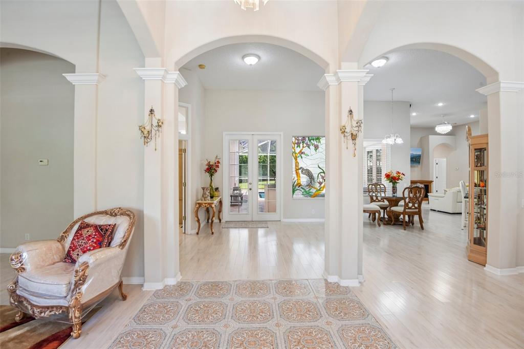 A bright foyer features arched entryways, tile and wood flooring, and a stained glass window — 1701 COUNTRY TRAILS DRIVE, SAFETY HARBOR, FL