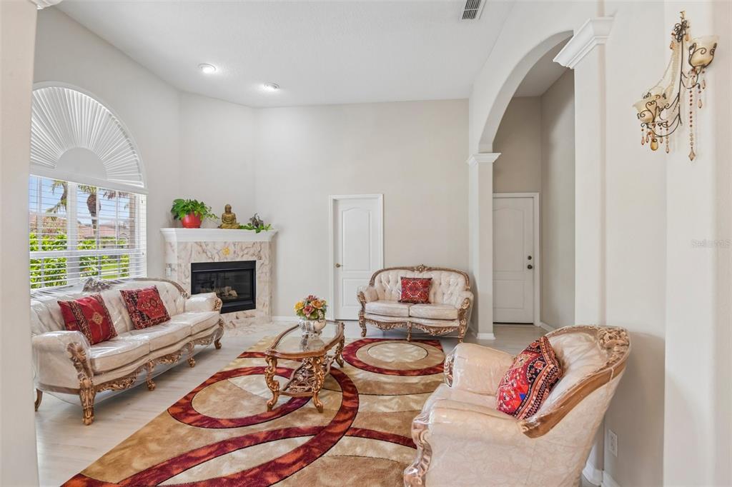 A living room features a fireplace, ornate furniture, a patterned rug, and an arched entryway — 1701 COUNTRY TRAILS DRIVE, SAFETY HARBOR, FL