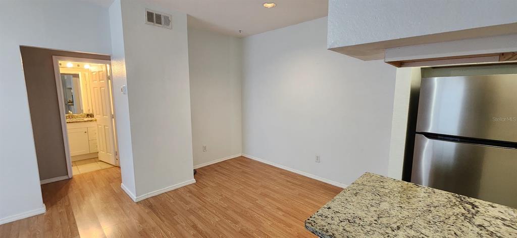 A kitchen area with wood-look flooring, a stainless steel refrigerator, and a doorway to a bathroom — 13015 SANCTUARY COVE DRIVE UNIT 203, TEMPLE TERRACE, FL