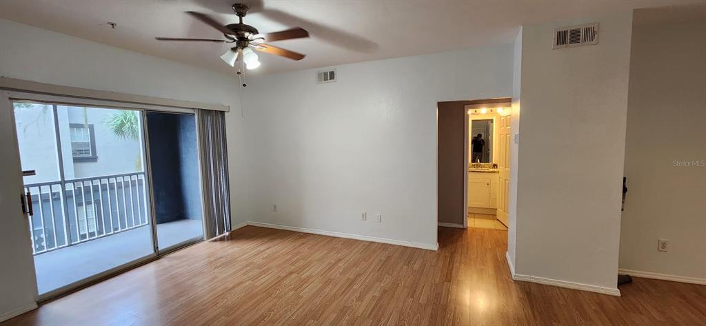 An empty room with wood-look flooring, a ceiling fan, and a sliding glass door to a balcony — 13015 SANCTUARY COVE DRIVE UNIT 203, TEMPLE TERRACE, FL