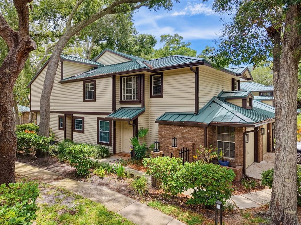 A beige house exterior features a front door, a walkway, and a potted plant — 1491 MAHOGANY LANE UNIT 1491, PALM HARBOR, FL