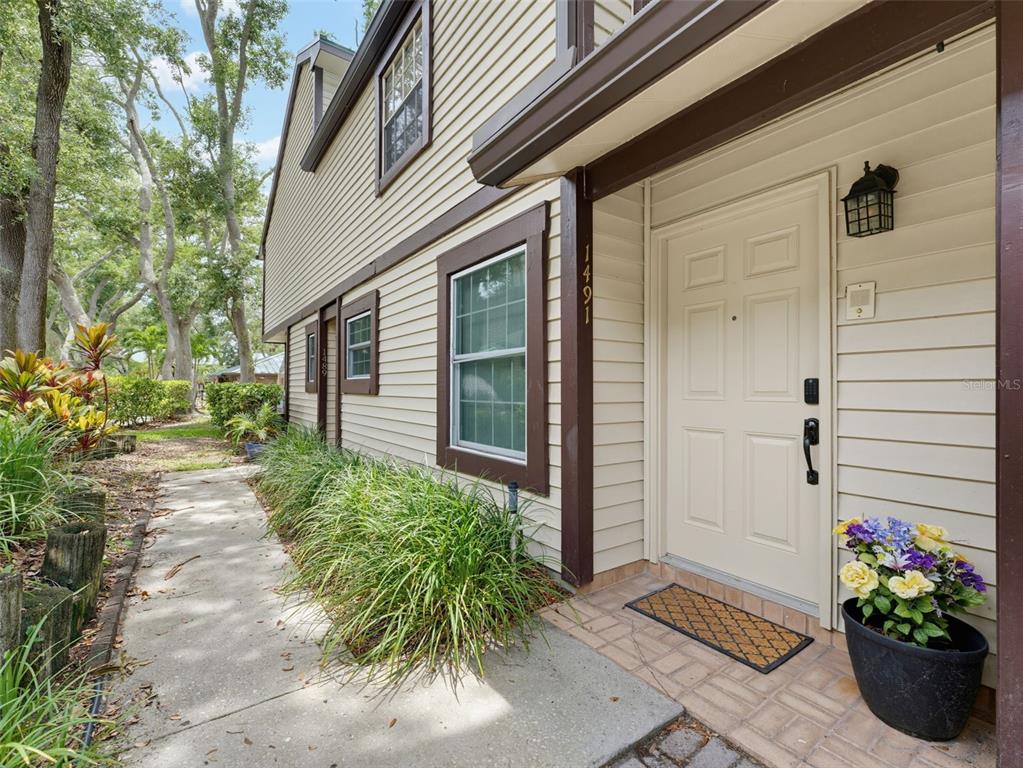 An entryway features a staircase with wood treads, white risers, and a white handrail — 1491 MAHOGANY LANE UNIT 1491, PALM HARBOR, FL