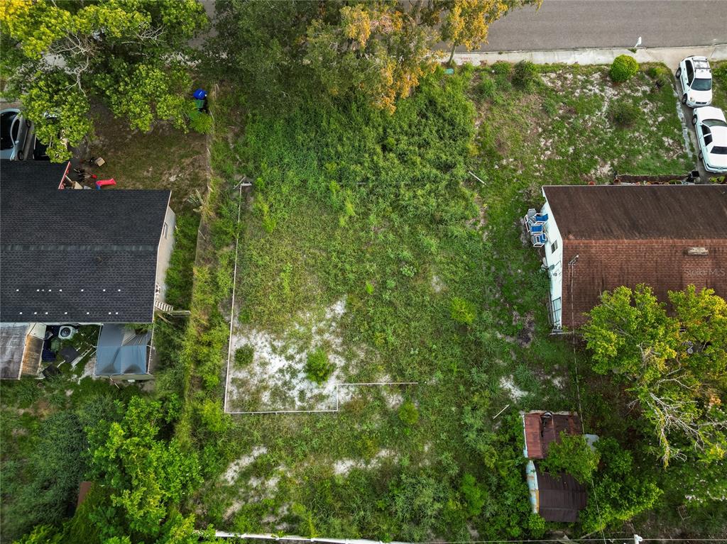 An aerial view shows a vacant, overgrown rectangular lot situated between two existing residential houses — 6114 W AMELIA STREET, ORLANDO, FL