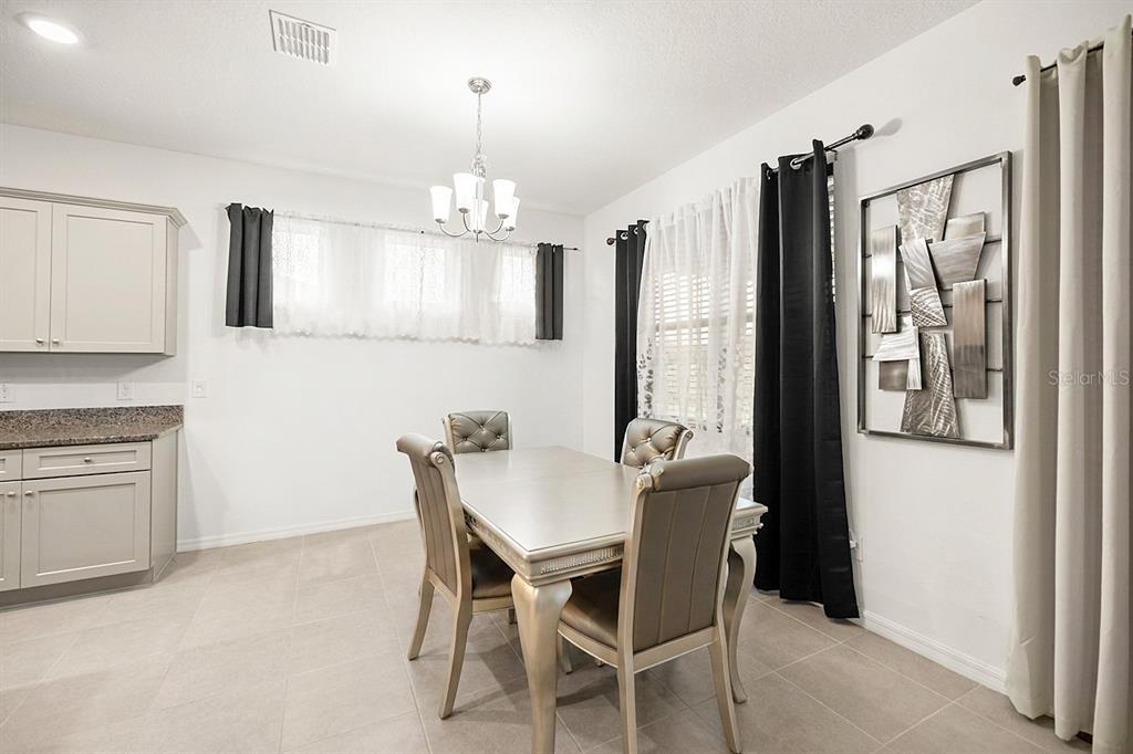 A dining area features a metallic table, four upholstered chairs, a chandelier, and wall art — 6474 SW 89TH LOOP, OCALA, FL
