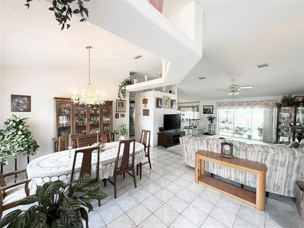 An open-concept dining and living area features tile flooring, a crystal chandelier, and sliding doors — 22 COLORADO DRIVE, PALM COAST, FL